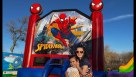 An action-packed backyard birthday party scene featuring a large Spider-Man inflatable bounce house combo with a red and blue slide. Families are gathered on the lawn, with adults chatting and children enjoying cotton candy and snow cones at nearby tables Youtube