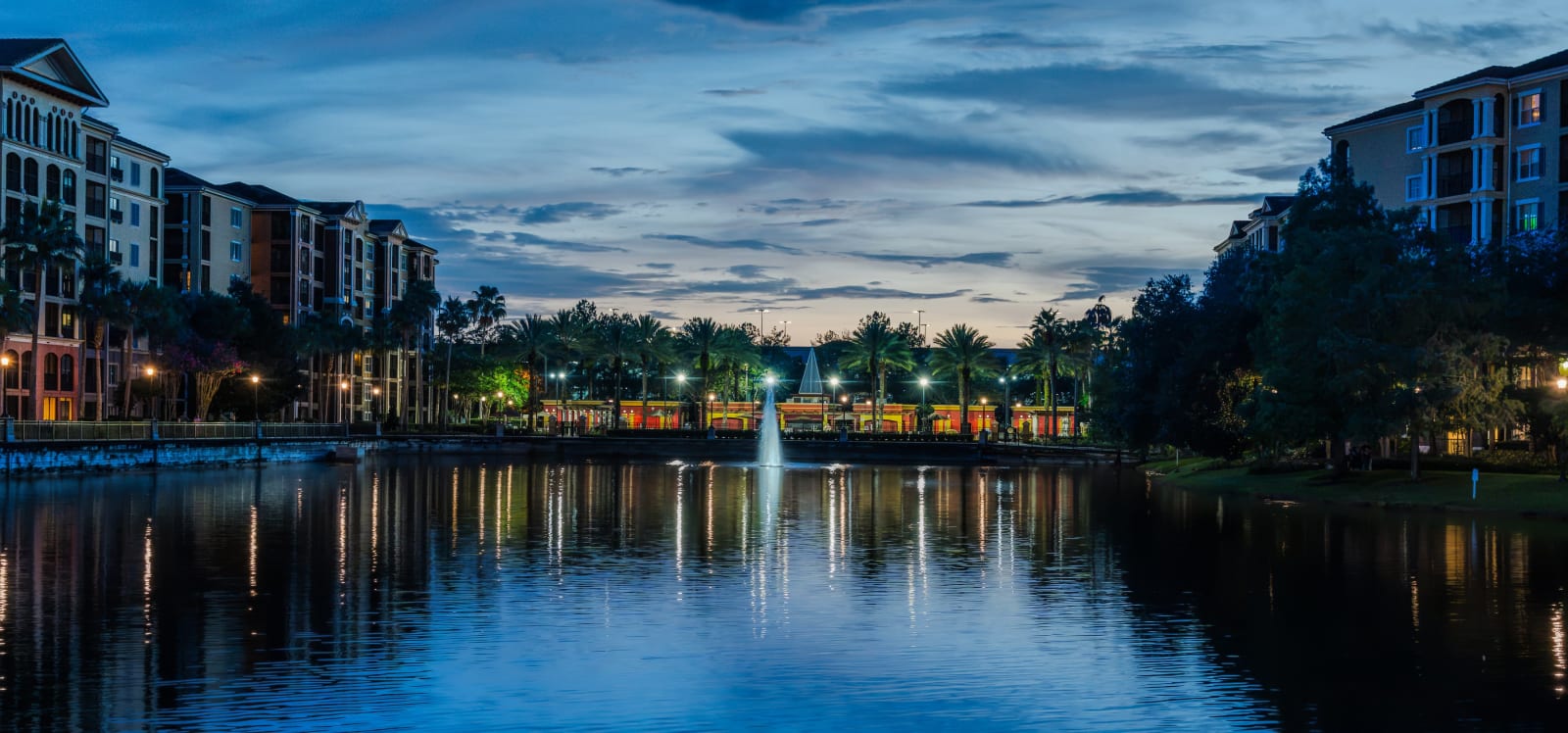 Blue hour cityscape with central fountain and reflection in still water