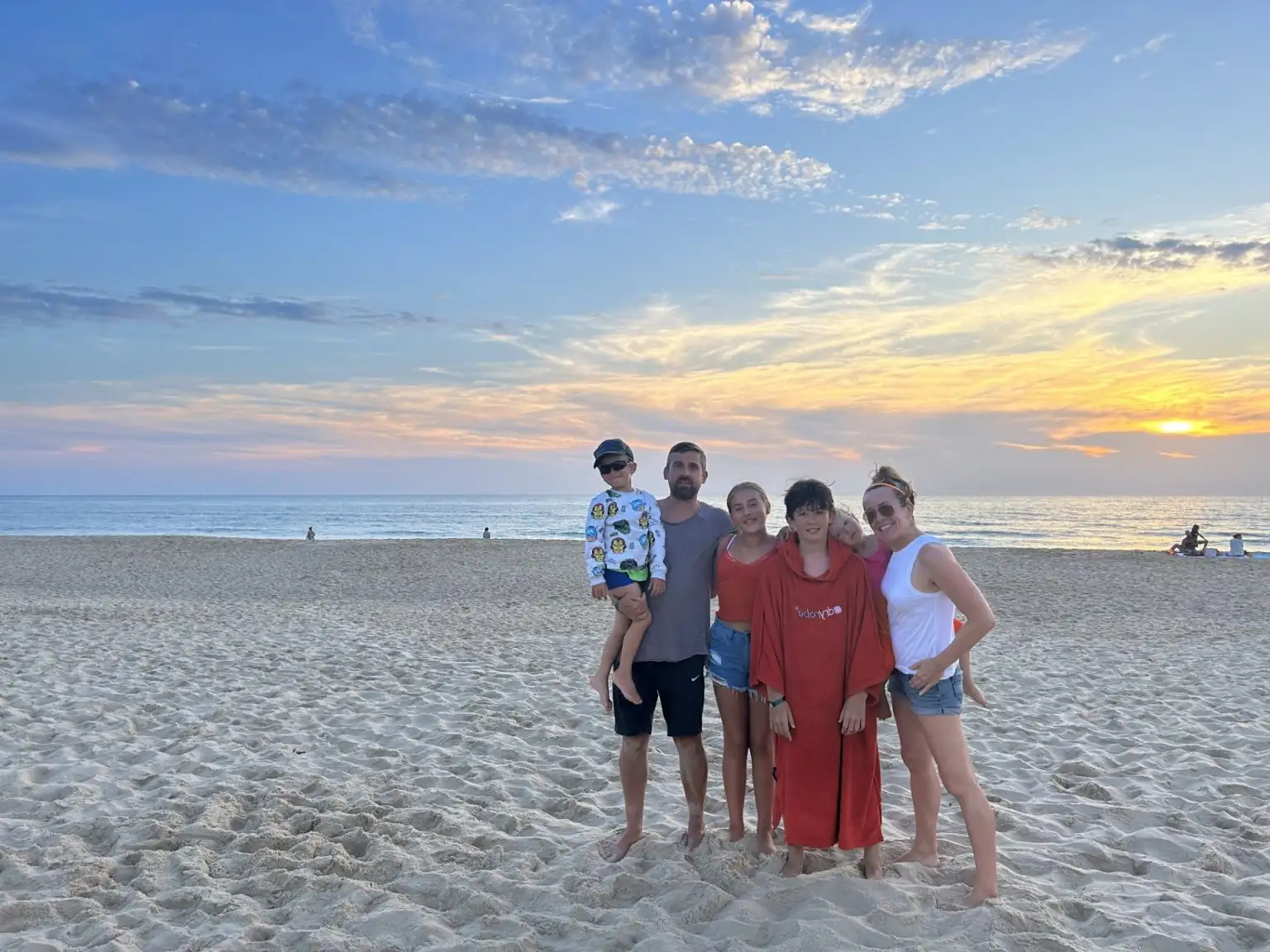 Family selfie outdoors with parents and three smiling children.