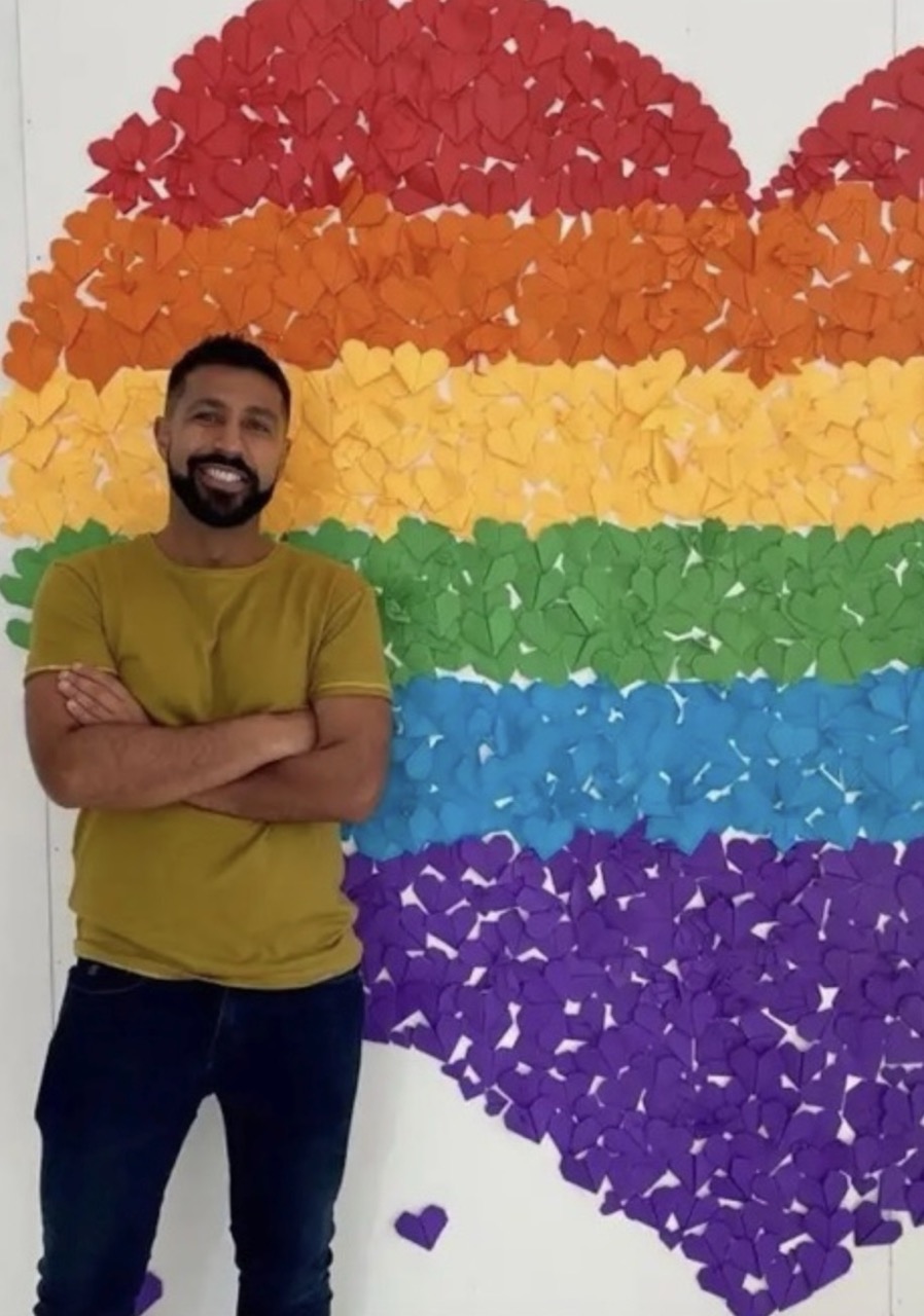 Man standing in front of rainbow heart wall art.