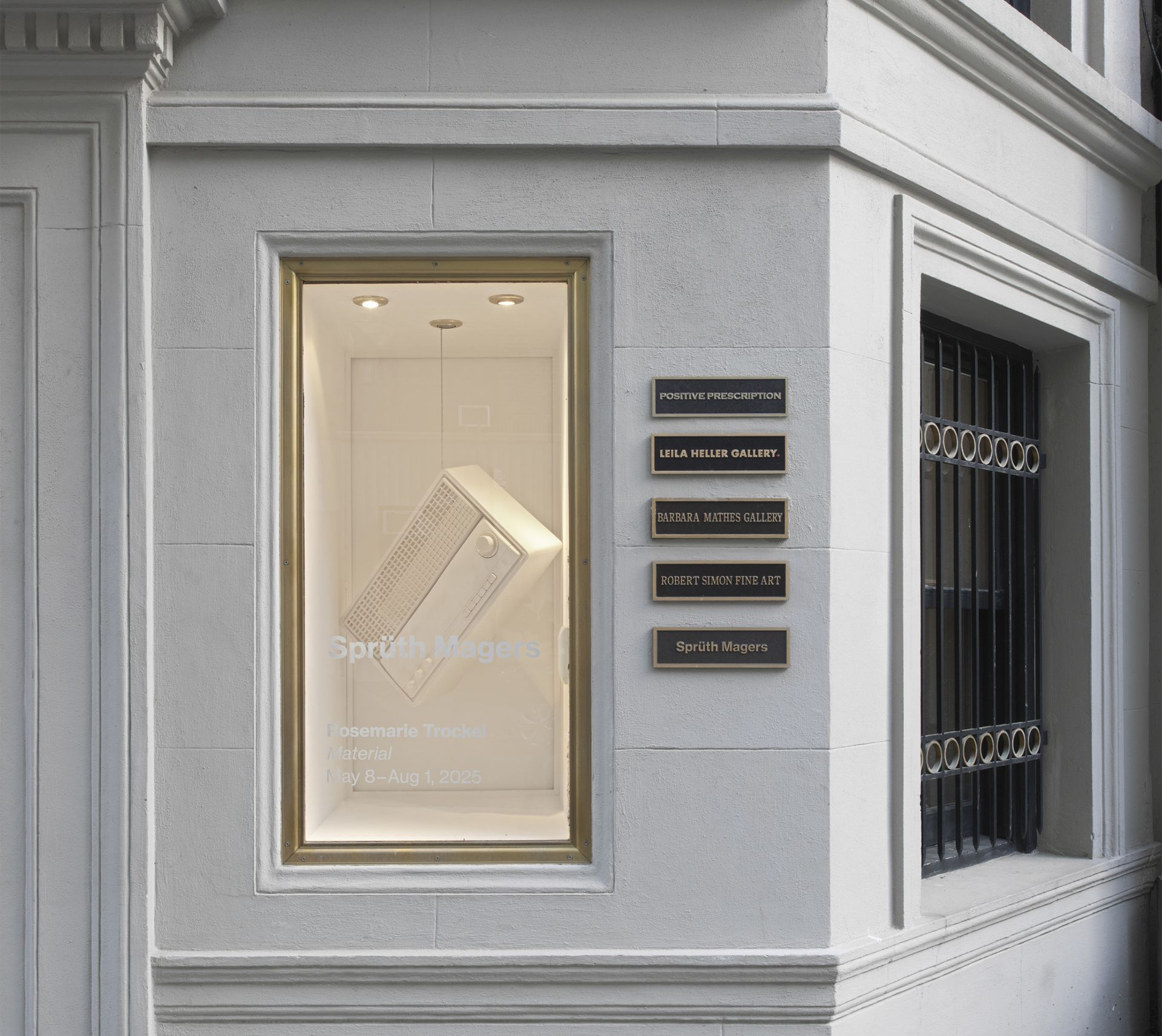 A display window of Sprüth Magers gallery featuring a vintage radio sculpture. Several gallery plaques are mounted on the adjacent wall.