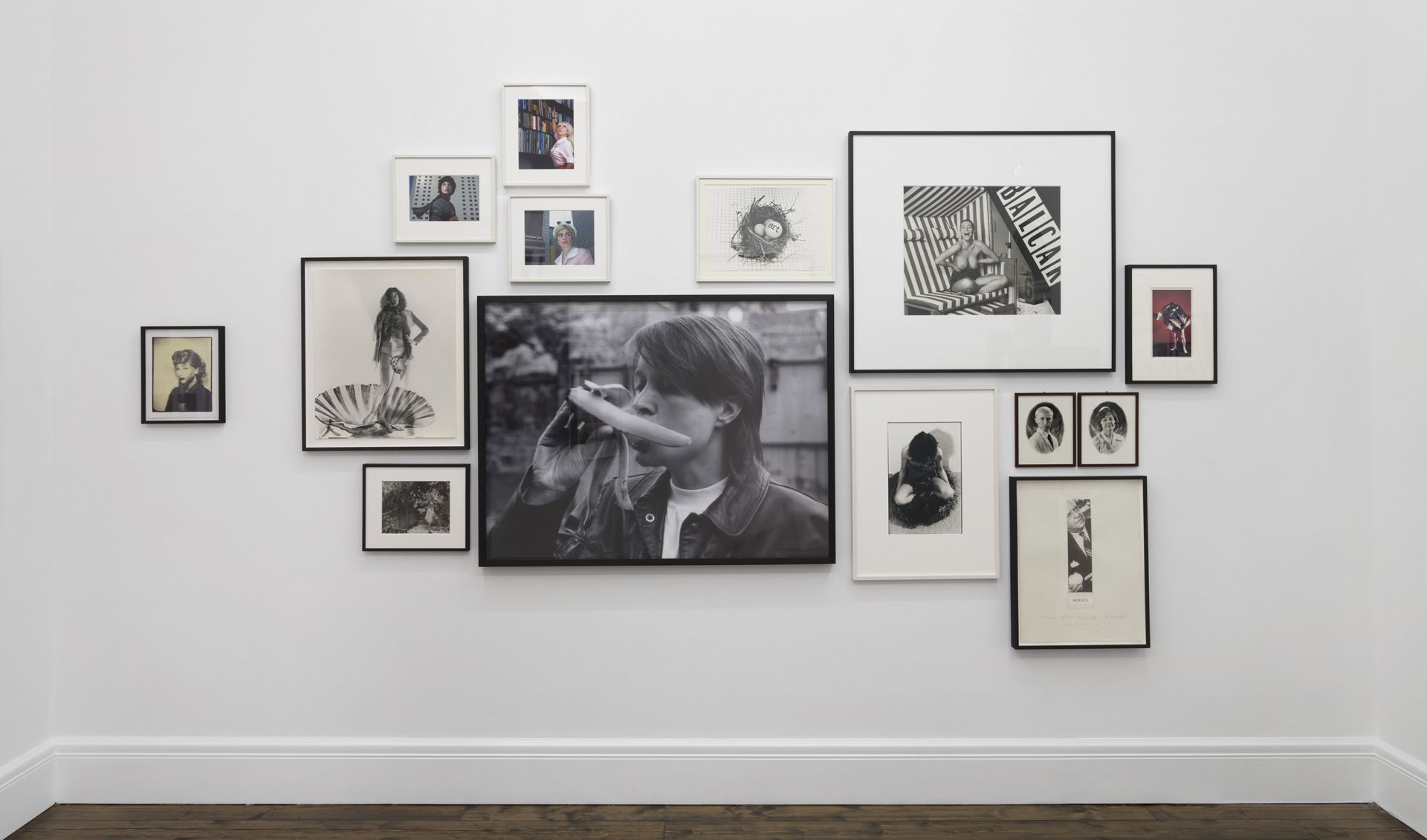 Salon-style wall arrangement of various sized black-and-white photographs and portraits with central larger image