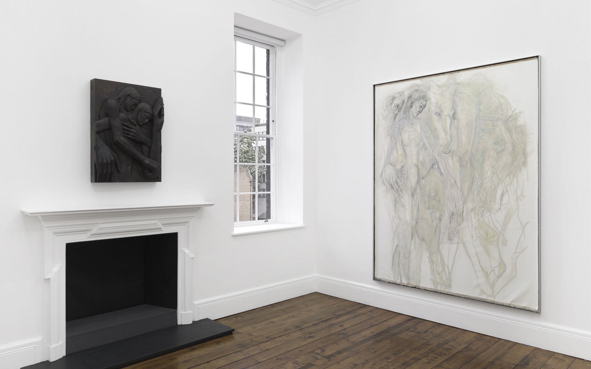 Gallery corner: dark bronze relief of embracing figures above a fireplace, beside a large pale painting of a figure with a horse.