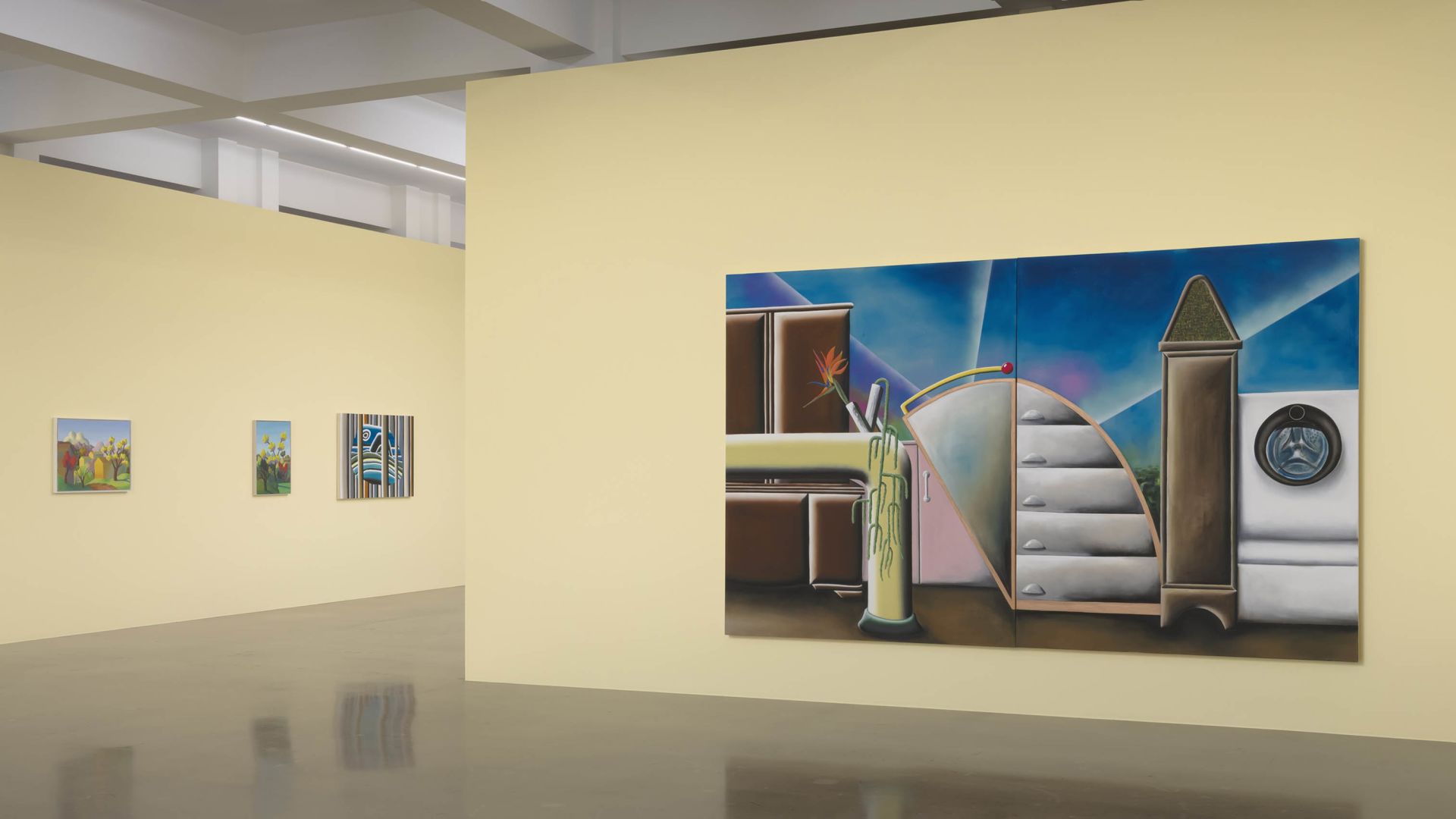 Gallery wall showing three small framed artworks and one large surreal painting with architectural elements, stairs, and cylindrical forms against a blue sky