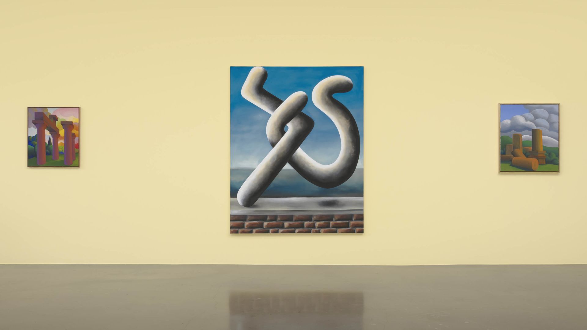 Gallery wall showing three framed paintings, with a large white sculptural form floating above brick base as the centerpiece