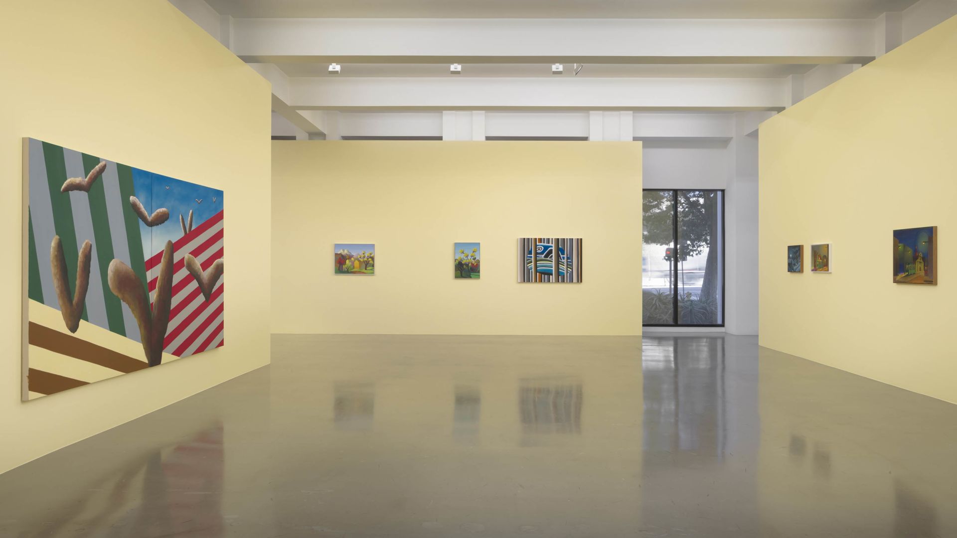 Modern art gallery interior with white walls, polished floors, and various framed paintings including a surreal artwork with geometric forms