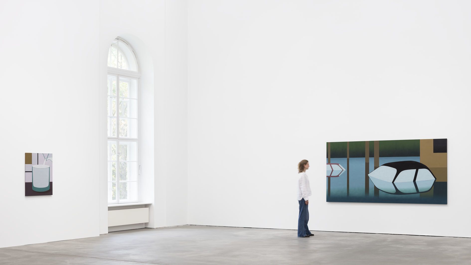 Gallery view showing person looking at paintings, including geometric works and a large piece with oval forms in blue and green.