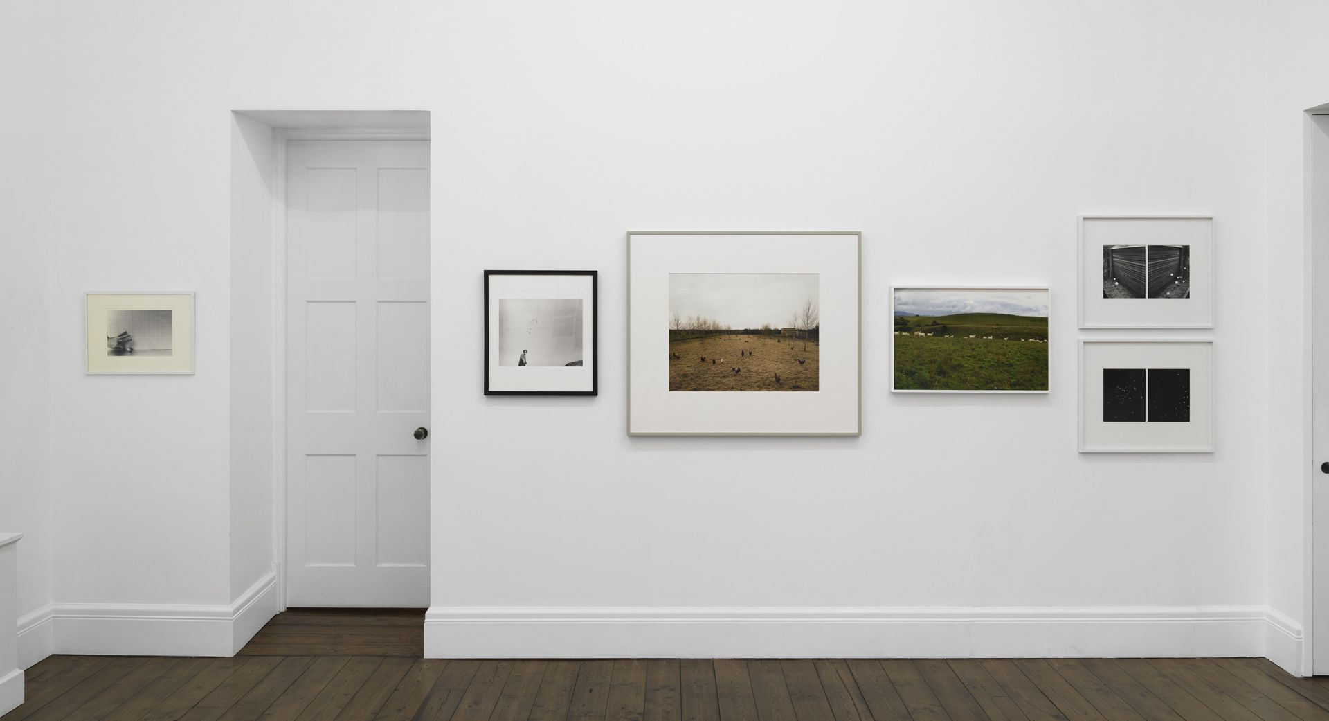Gallery wall with landscape photographs including rural scenes, fields, and abstract dark images.