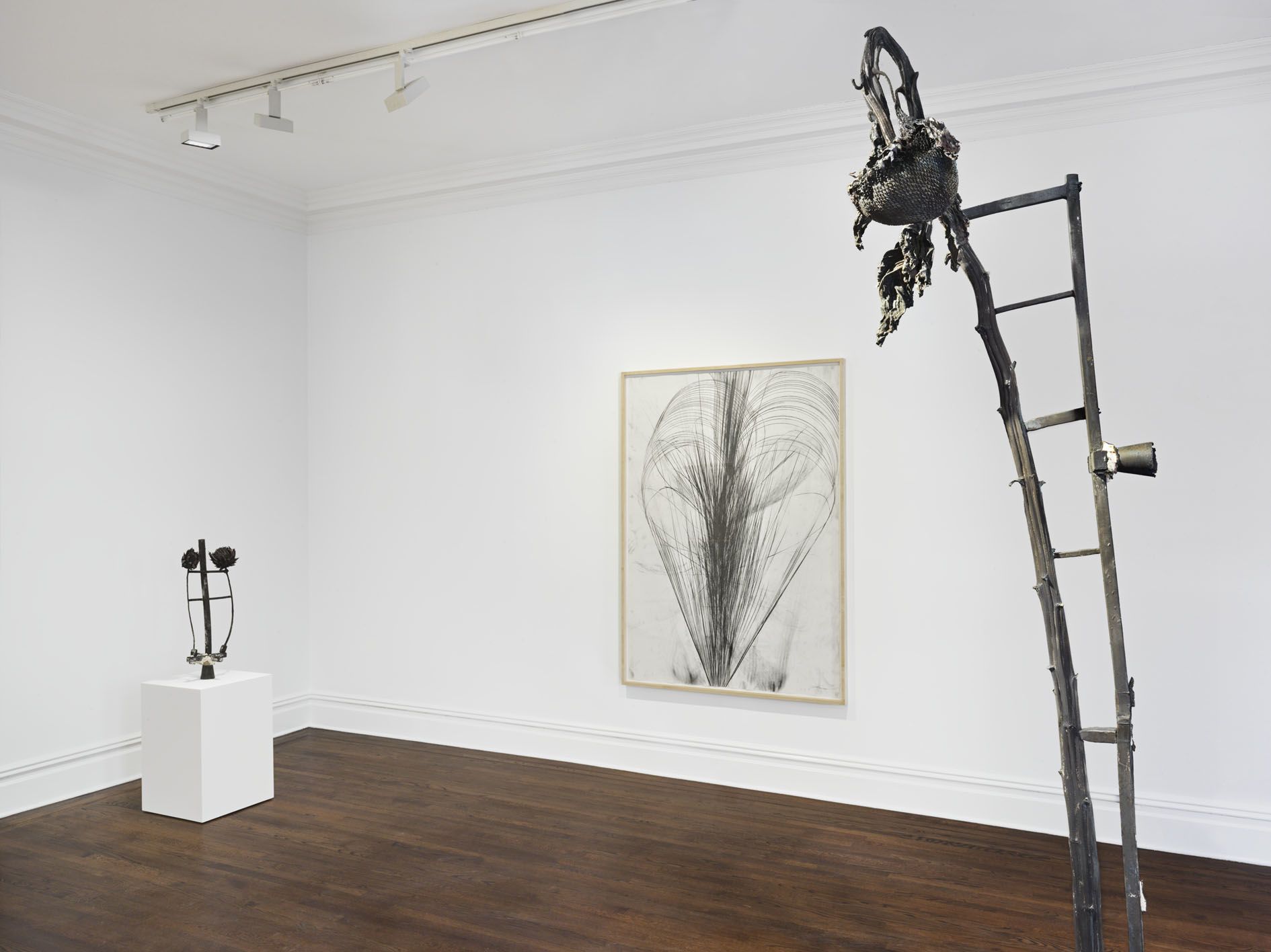 Gallery corner with tall ladder sculpture and framed graphite drawing on white wall