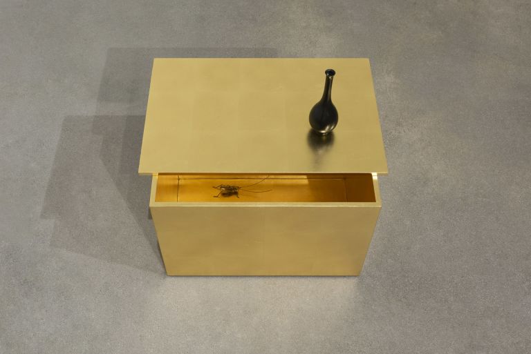 Haris Epaminonda
Untitled #02 a/j, 2020
Box with brass gilding on wood, lid with brass gilding on wood and black ink on chalk base, black patinated old bronze vase, brass cricket and framed found book page
Holzkasten: 30 × 45 × 28 cm
Holzdeckel/ Vase: 16.5 × 6 × 6 cm
Grille: 14 × 5 × 5 cm 
Gerahmte Buchseite: 30.9 × 23.7 × 2.5 cm
Box: 11 7/8 × 17 3/4 × 11 inches
Lid/ Vase:6 1/2 × 2 3/8 × 2 3/8 inches
Cricket: 1/2 × 2 × 2 inches
Framed book page: 12 1/8 × 9 1/4 × 1 inches
Edition unique