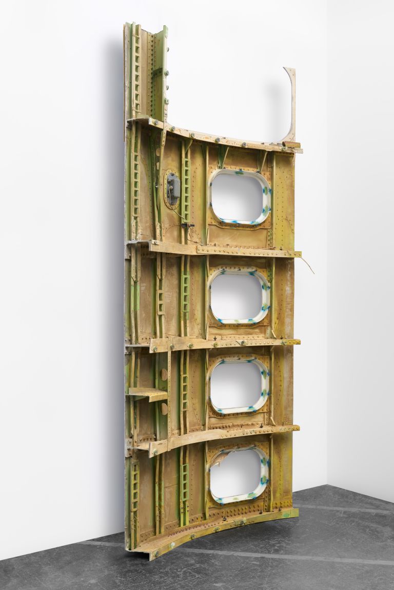 Blue panel with four rounded rectangular cutouts, appearing to be repurposed aircraft or industrial material with red and white striped detail at bottom