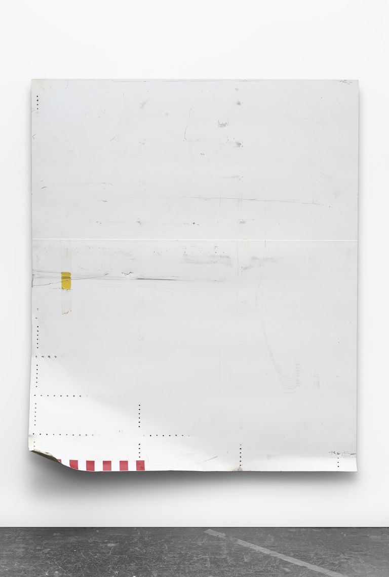 Minimalist white artwork with subtle markings, perforations, and a small yellow element. Red and white stripes visible at the bottom corner