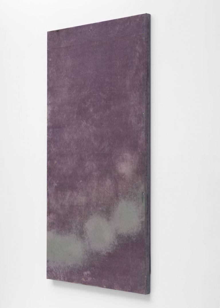 Eight purple abstract paintings arranged in a horizontal line on a white gallery wall, featuring cloudy, atmospheric textures.