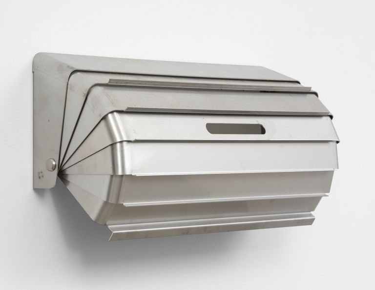 Geometric metal wall sculpture with layered angular forms in silver/gray finish, creating dimensional shadow patterns.