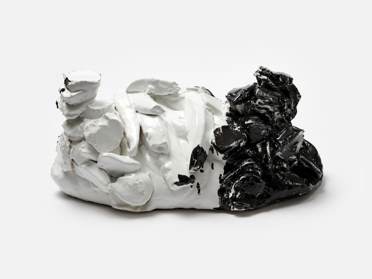 A sculptural ceramic object half white and half black with textured, organic forms, photographed against a white background.