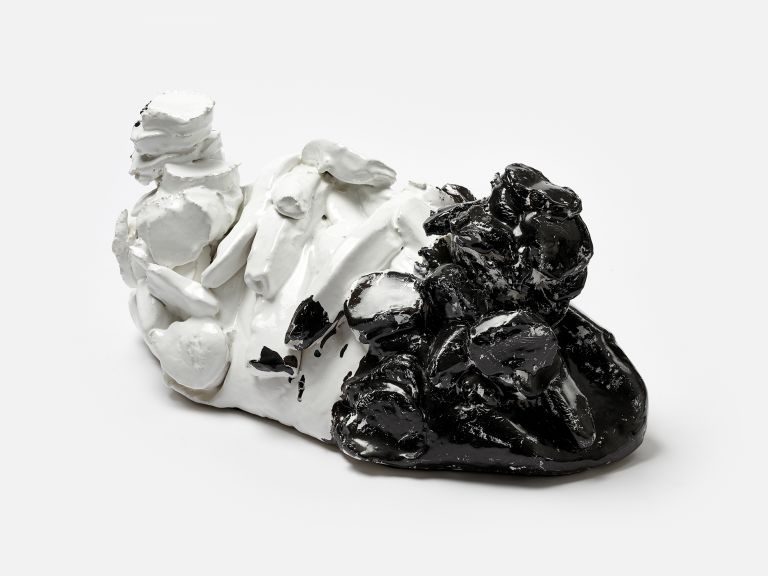 A sculptural ceramic object half white and half black with textured, organic forms, photographed against a white background.