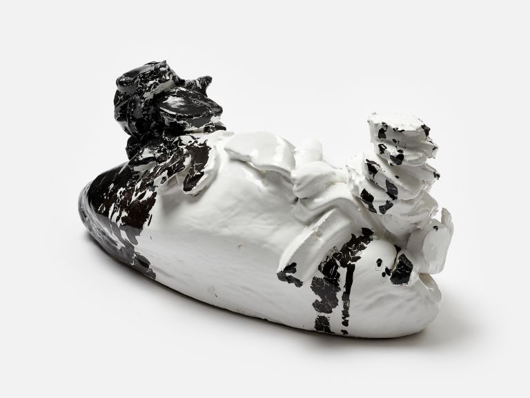 A sculptural ceramic object half white and half black with textured, organic forms, photographed against a white background.