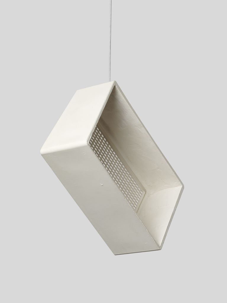 A vintage cream-colored sculpture of a radio suspended by a thin wire against a light gray background. The radio has a rectangular design with a speaker grille, control knob, and several buttons.