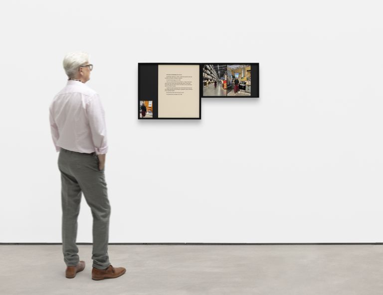Close-up of framed exhibition panel featuring text about "The Public Performance of the Self" with accompanying photographs of retail spaces.