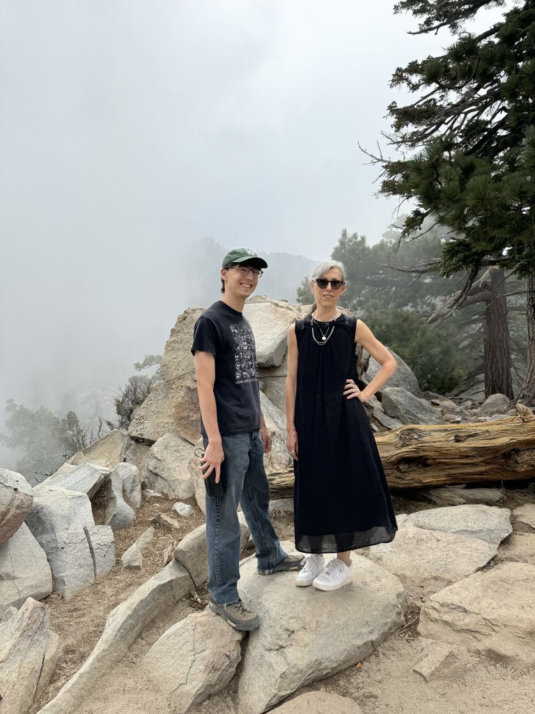 Framed artwork displaying text and photographs of performance art conducted in rocky, mountainous outdoor terrain with multiple participants.