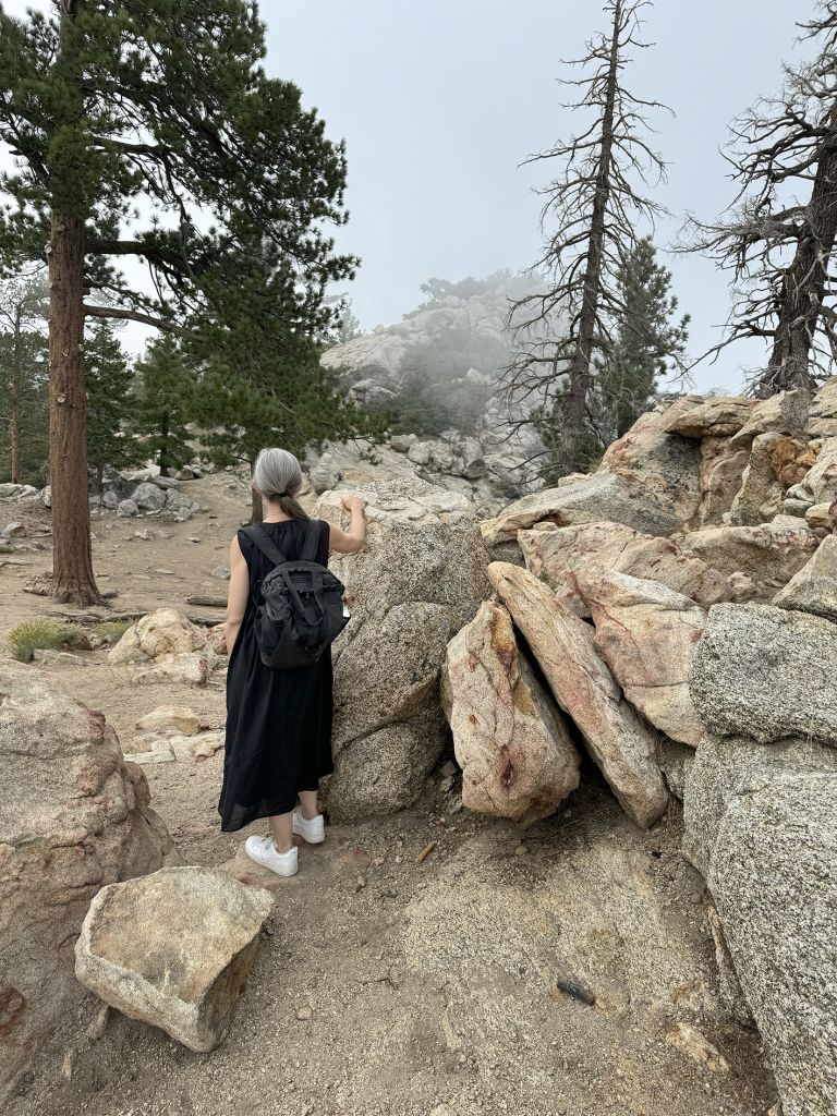 Framed artwork displaying text and photographs of performance art conducted in rocky, mountainous outdoor terrain with multiple participants.