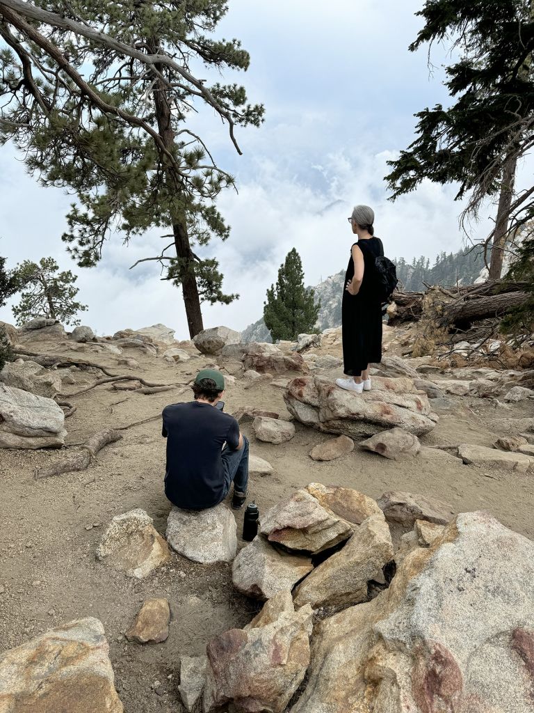 Framed artwork displaying text and photographs of performance art conducted in rocky, mountainous outdoor terrain with multiple participants.