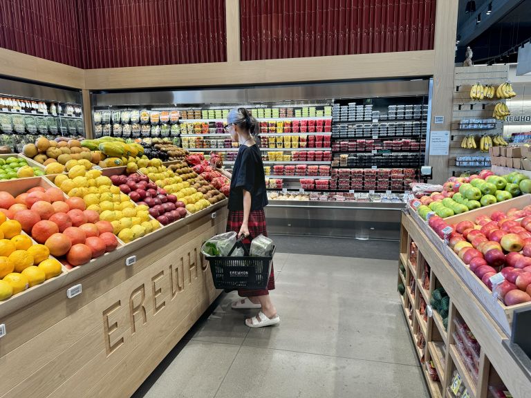 Large horizontal frame containing text panel and photographs showing grocery store performances with produce sections and shopping aisles.