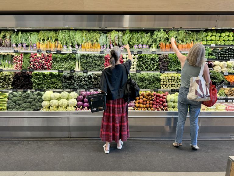 Large horizontal frame containing text panel and photographs showing grocery store performances with produce sections and shopping aisles.