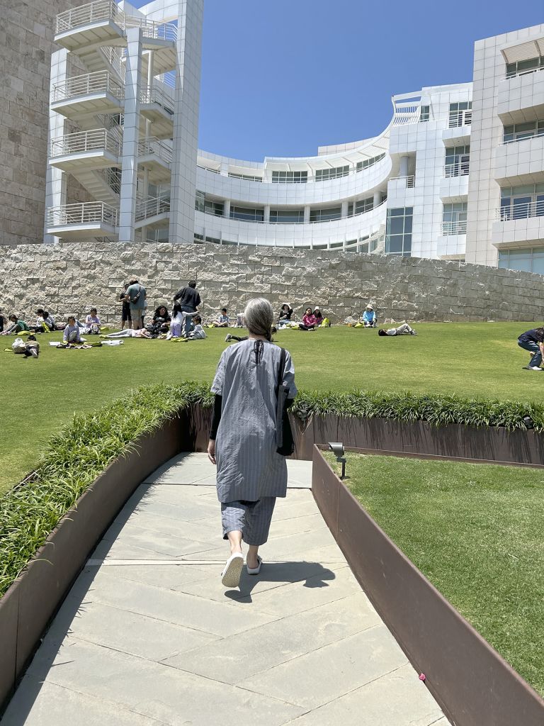 Exhibition panel featuring photographs of institutional building exterior and group of people, with accompanying descriptive text about performance.