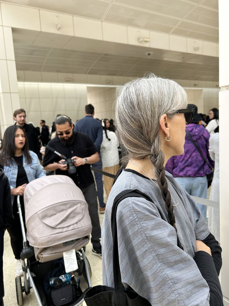 Exhibition panel featuring photographs of institutional building exterior and group of people, with accompanying descriptive text about performance.