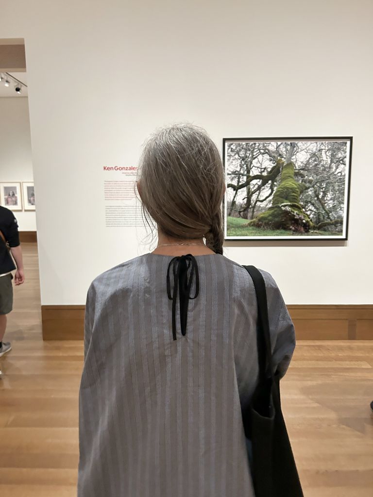 Exhibition panel featuring photographs of institutional building exterior and group of people, with accompanying descriptive text about performance.