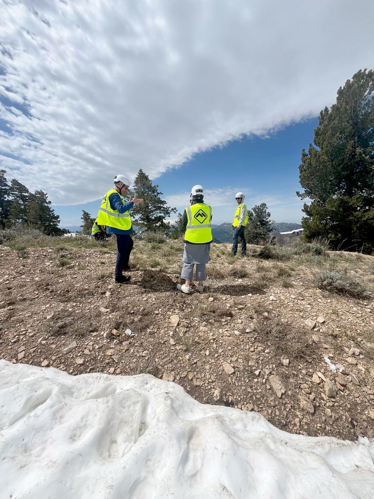 Frame displaying text and photographs of construction or work site performance with people in safety vests in mountainous terrain.