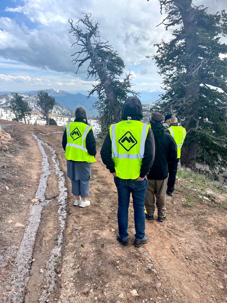 Frame displaying text and photographs of construction or work site performance with people in safety vests in mountainous terrain.