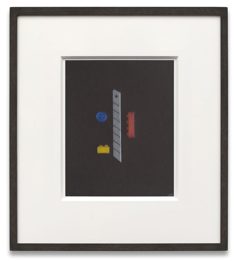 Framed artwork with dark background featuring geometric shapes - a blue button, yellow and red lego bricks, and gray cutter blade.