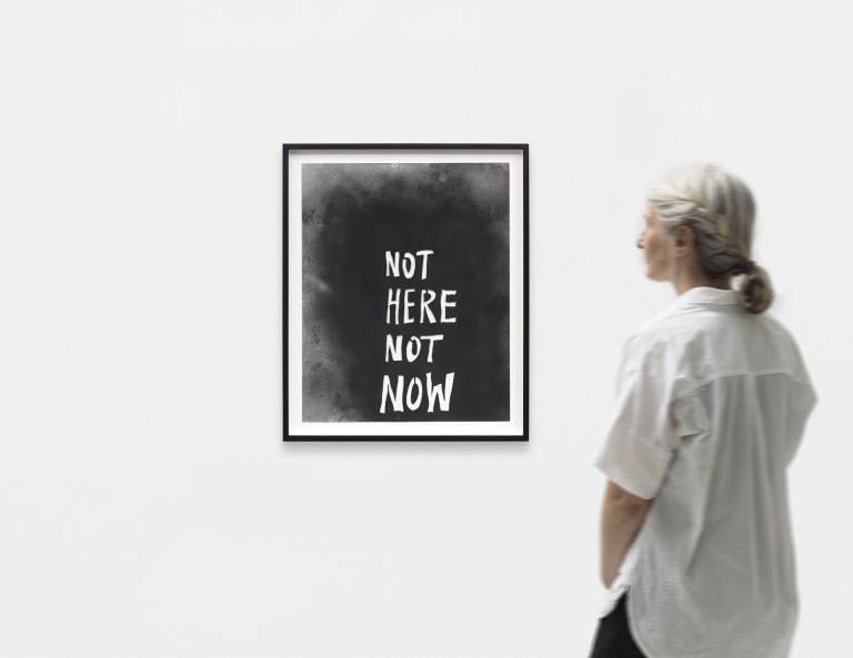 Monochrome watercolor piece featuring "NOT HERE NOT NOW" in white text on a dark, cloudy wash background, presented in a black frame.