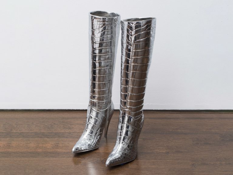 Pair of silver metallic crocodile-textured knee-high boots on wooden floor.