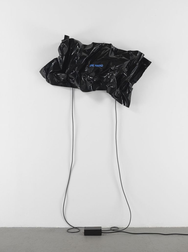 Black heat-folded vinyl sheet mounted on wall with blue neon text reading 'DIE HARD'