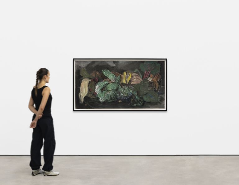 Still life painting of vegetables and produce including leafy greens, carrots, and root vegetables arranged dramatically against a dark background.
