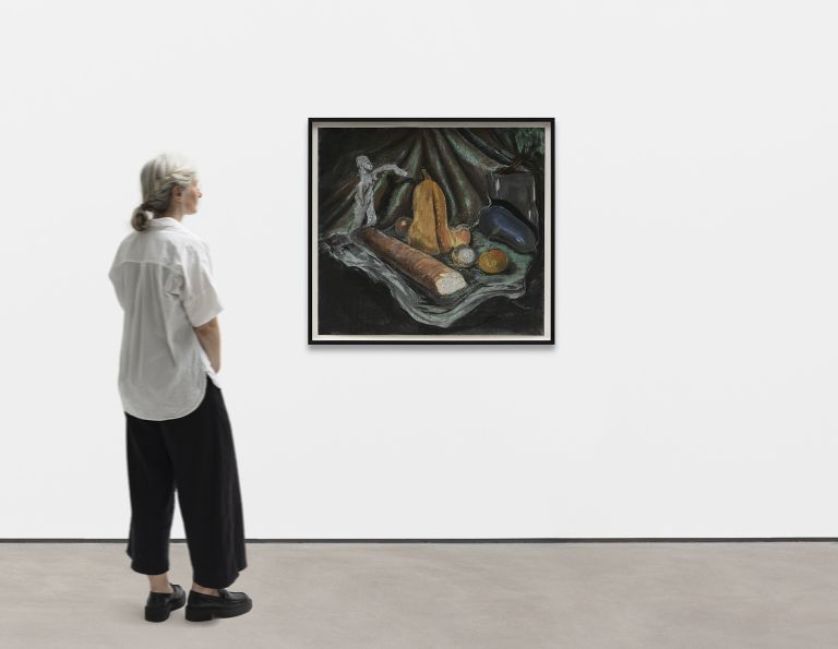 Still life painting with bread, squash, and produce arranged on draped green and gray fabric against a dark background.