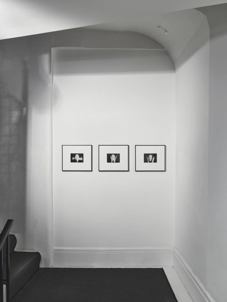 Three small framed black and white portrait photographs hung in a row on a white gallery wall with vaulted ceiling