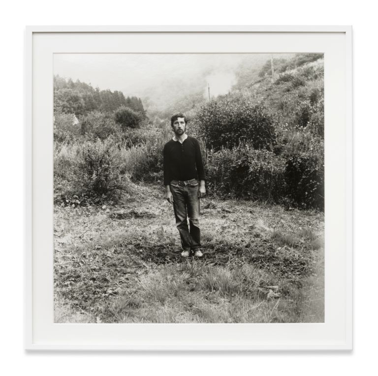 Grid of nine identical black and white photographs showing a person gradually disappearing into a landscape.