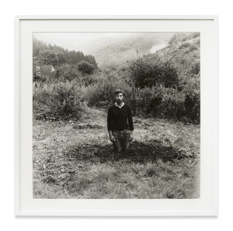 Grid of nine identical black and white photographs showing a person gradually disappearing into a landscape.