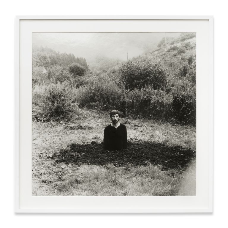 Grid of nine identical black and white photographs showing a person gradually disappearing into a landscape.