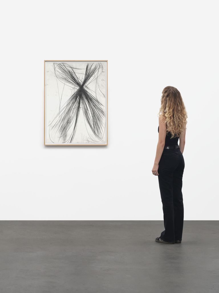 Framed abstract drawing showing X-shaped black graphite burst with radiating lines on white background