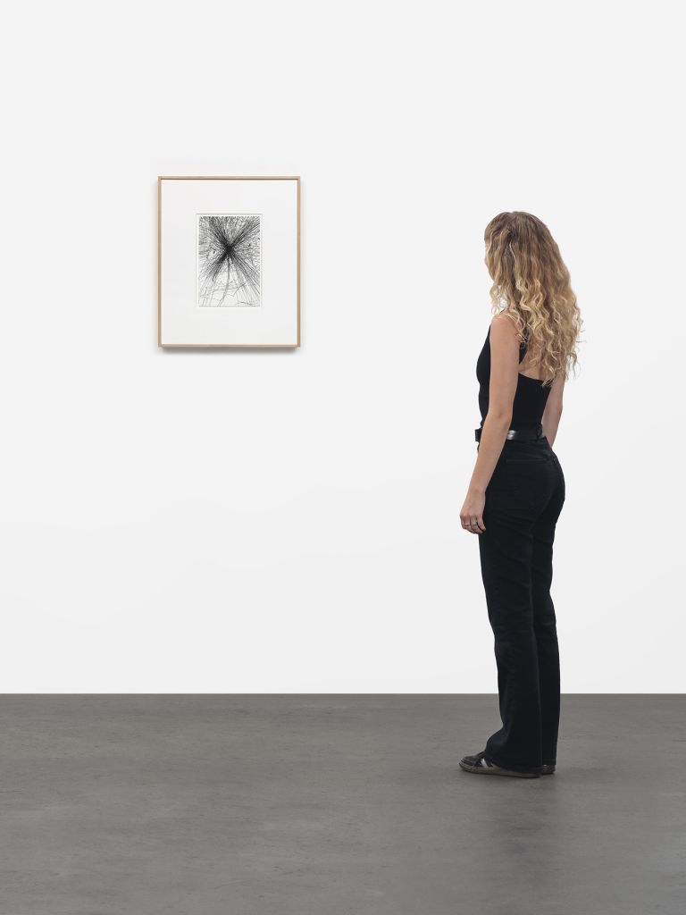 Framed drawing of radiating black graphite lines bursting from central point, matted in white