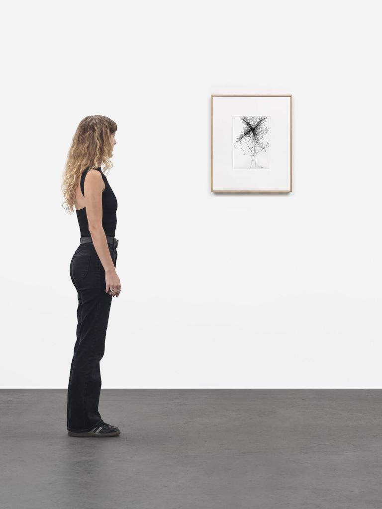 Framed drawing of X-shaped black graphite burst with flowing lines, matted in white frame