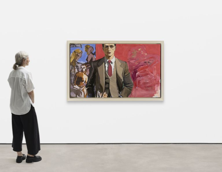 Man in brown suit and red tie stands before a red abstract background, with two women in blue panel.