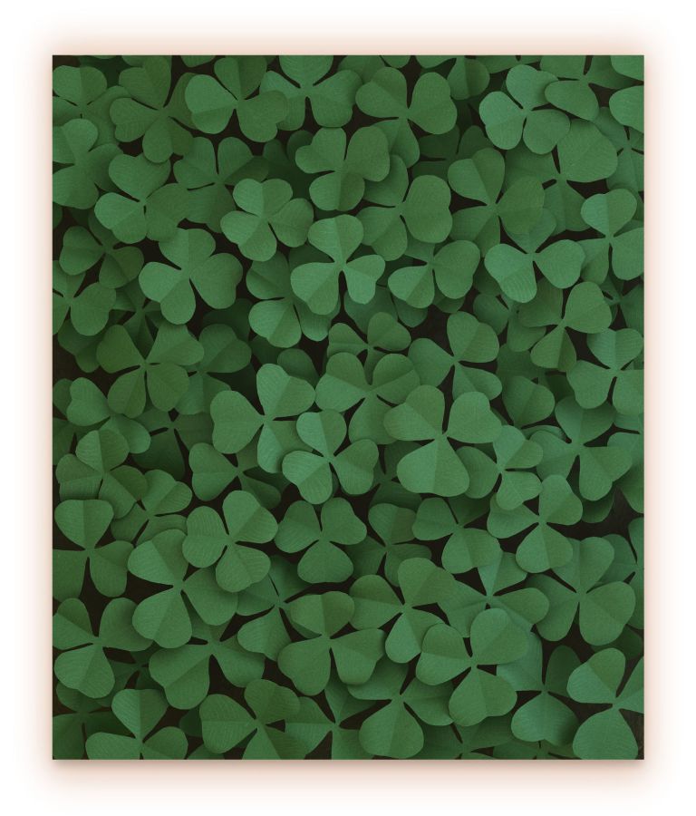 Photograph of densely packed green shamrocks filling entire frame, varying shades of emerald green.