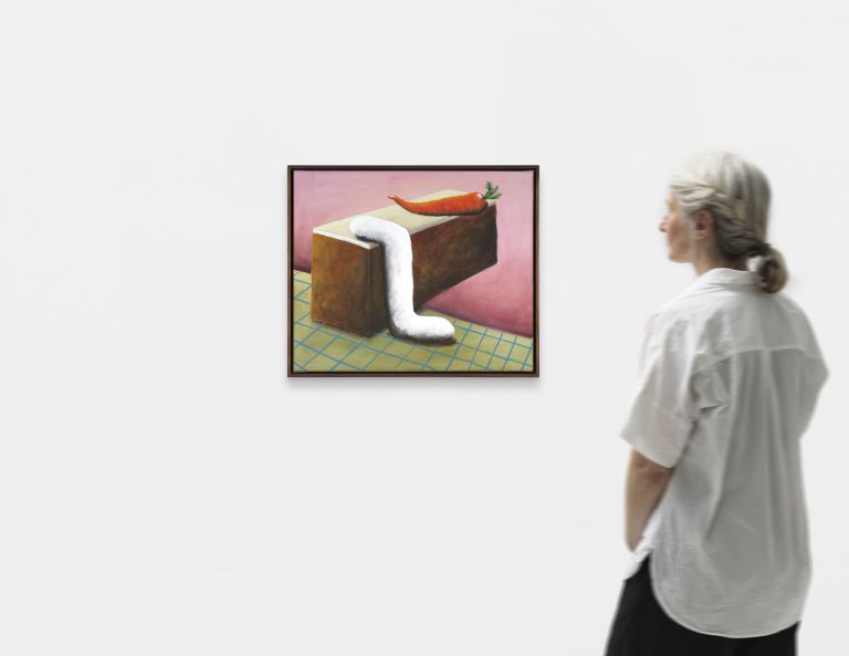 Framed painting of a rectangular cake block with dripping white icing and a single carrot on top, on a grid surface.