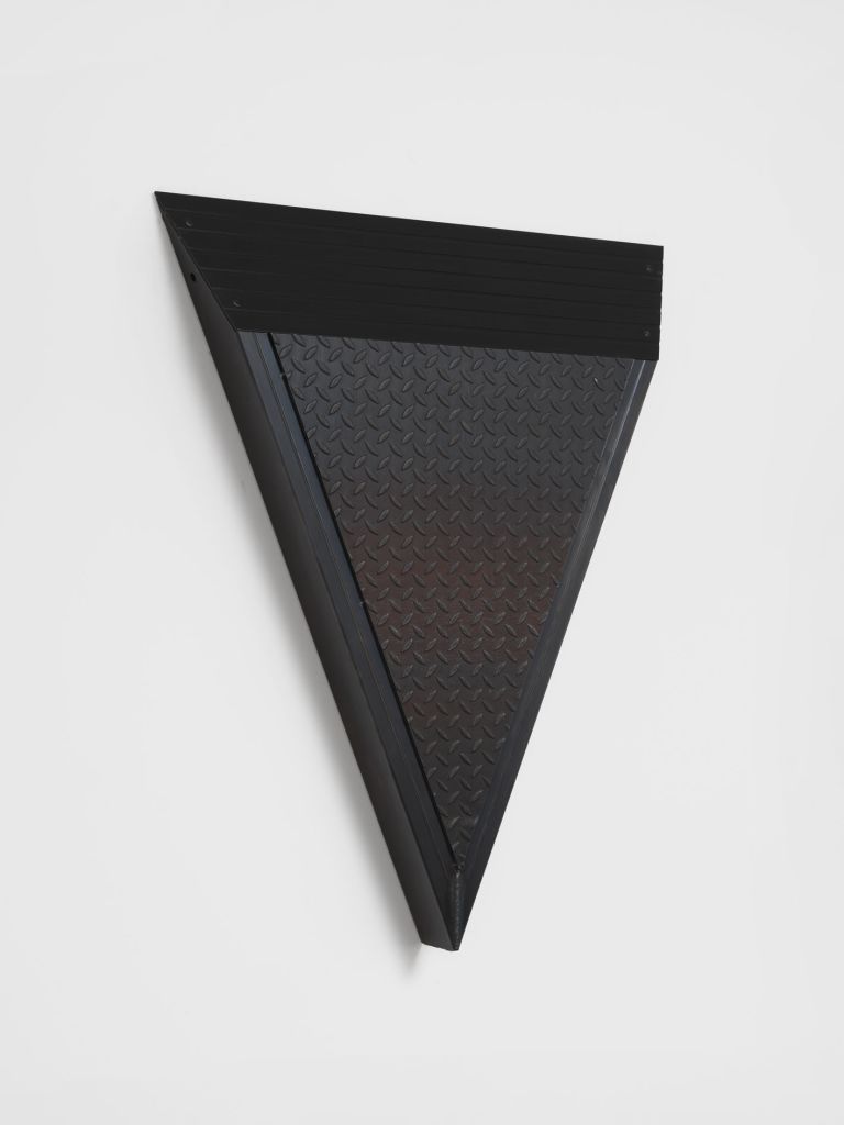 Black metal wall sculpture in downward-pointing triangle form, combining ribbed upper panel and diamond-plate textured lower surface.